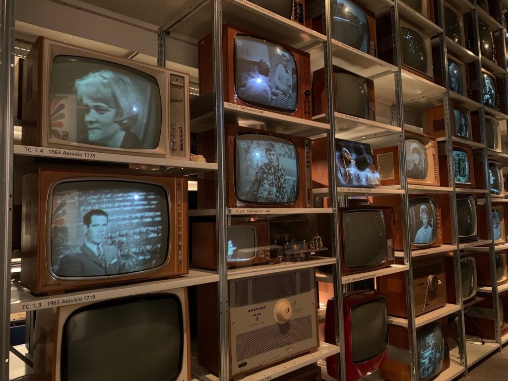 Hyllyssä paljon vanhoja tekevisioita, joissa kuvat vanhoista televisio-ohjelmista.